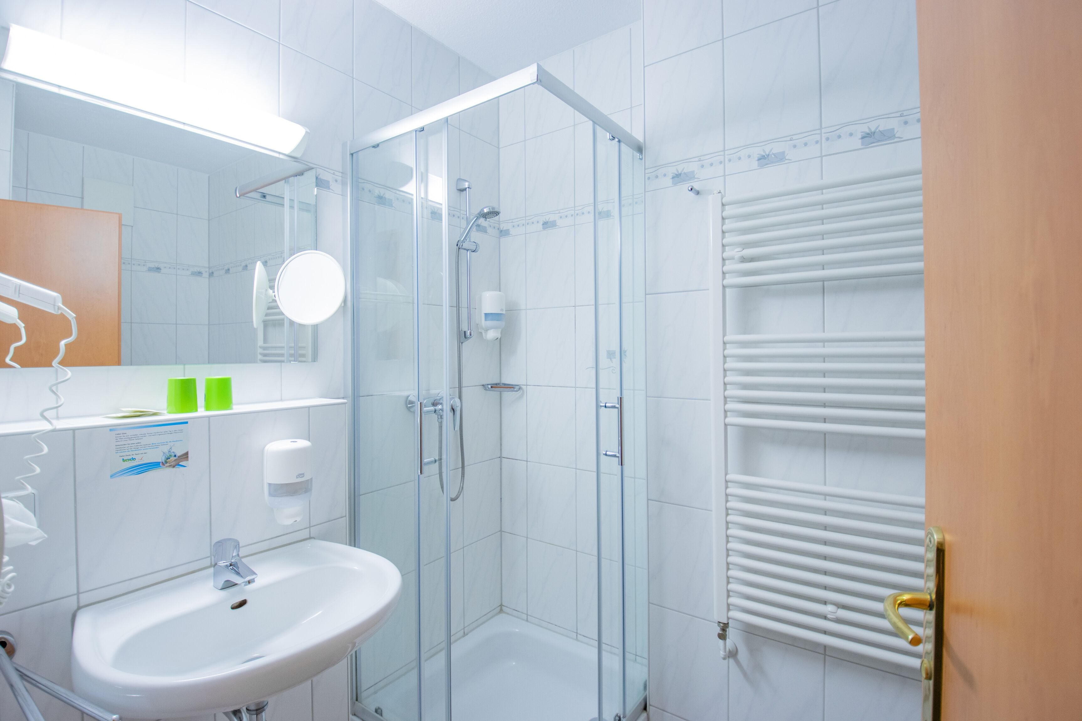A modern bathroom with a glass-enclosed shower, a white sink, and a towel rack.