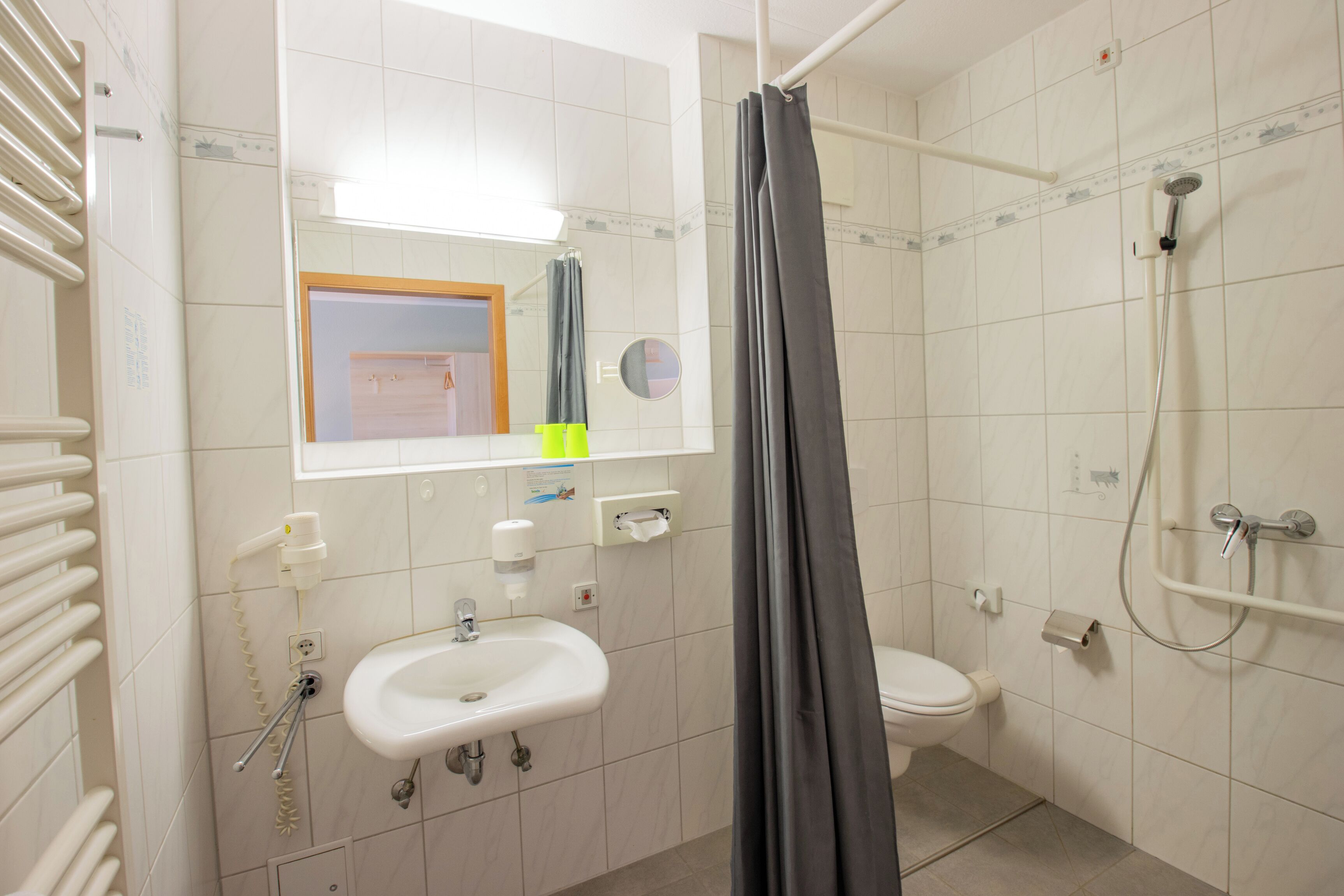 A bathroom with a sink, toilet, shower, and a mirror.