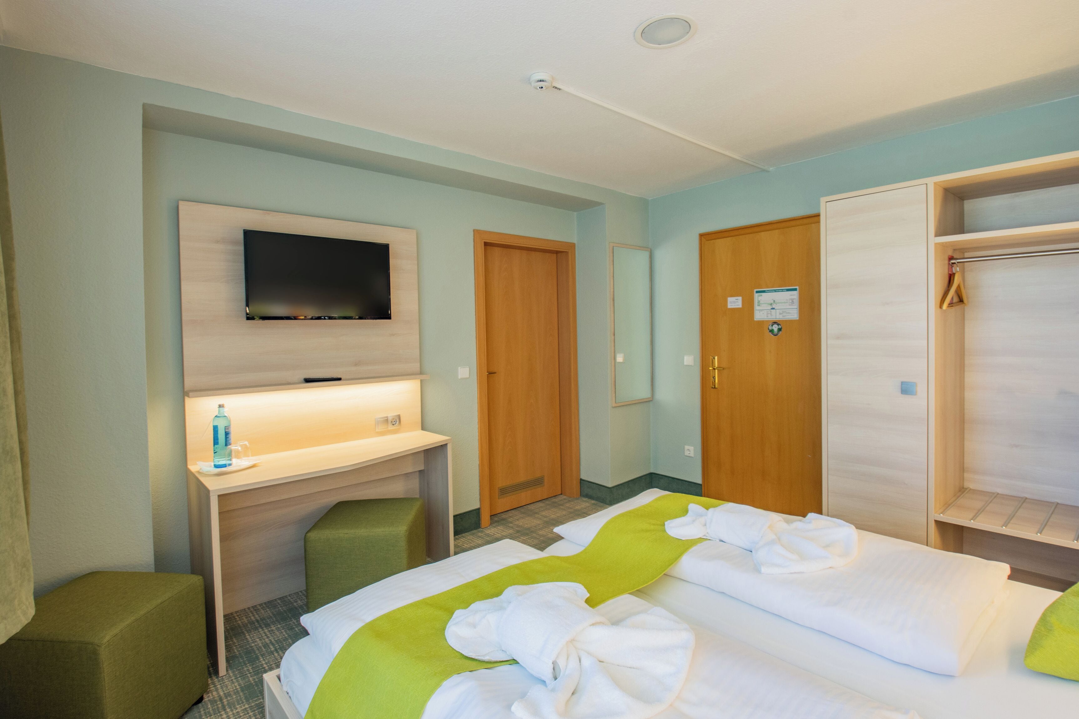 Une chambre d’hôtel avec un lit, un bureau, une télévision et une armoire.