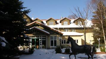 A two-story building with a snow-covered roof and a horse statue in front.