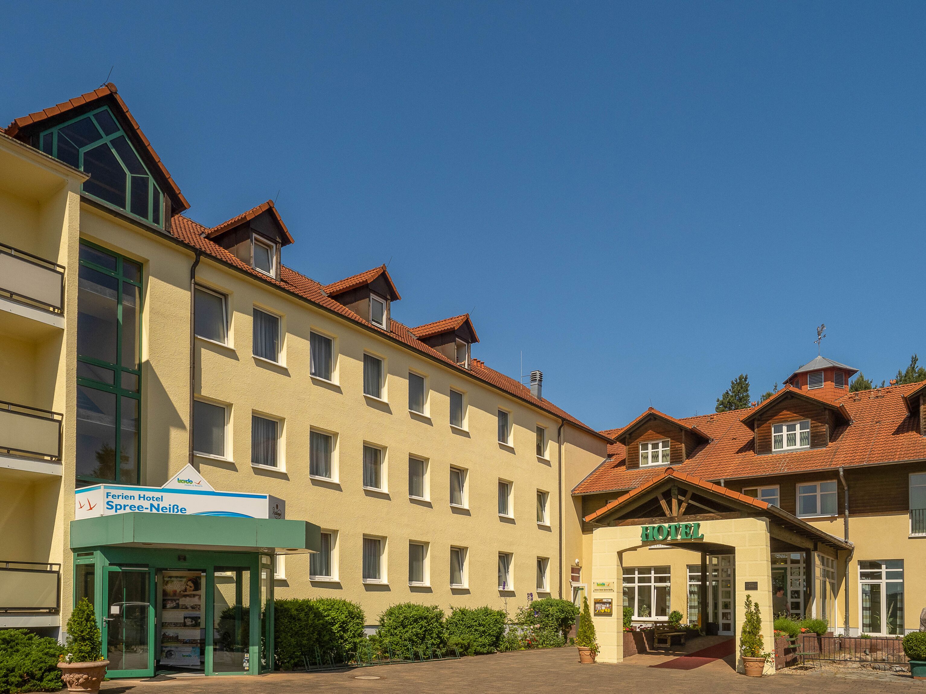 A hotel with a green entrance, multiple windows, and a tiled roof.