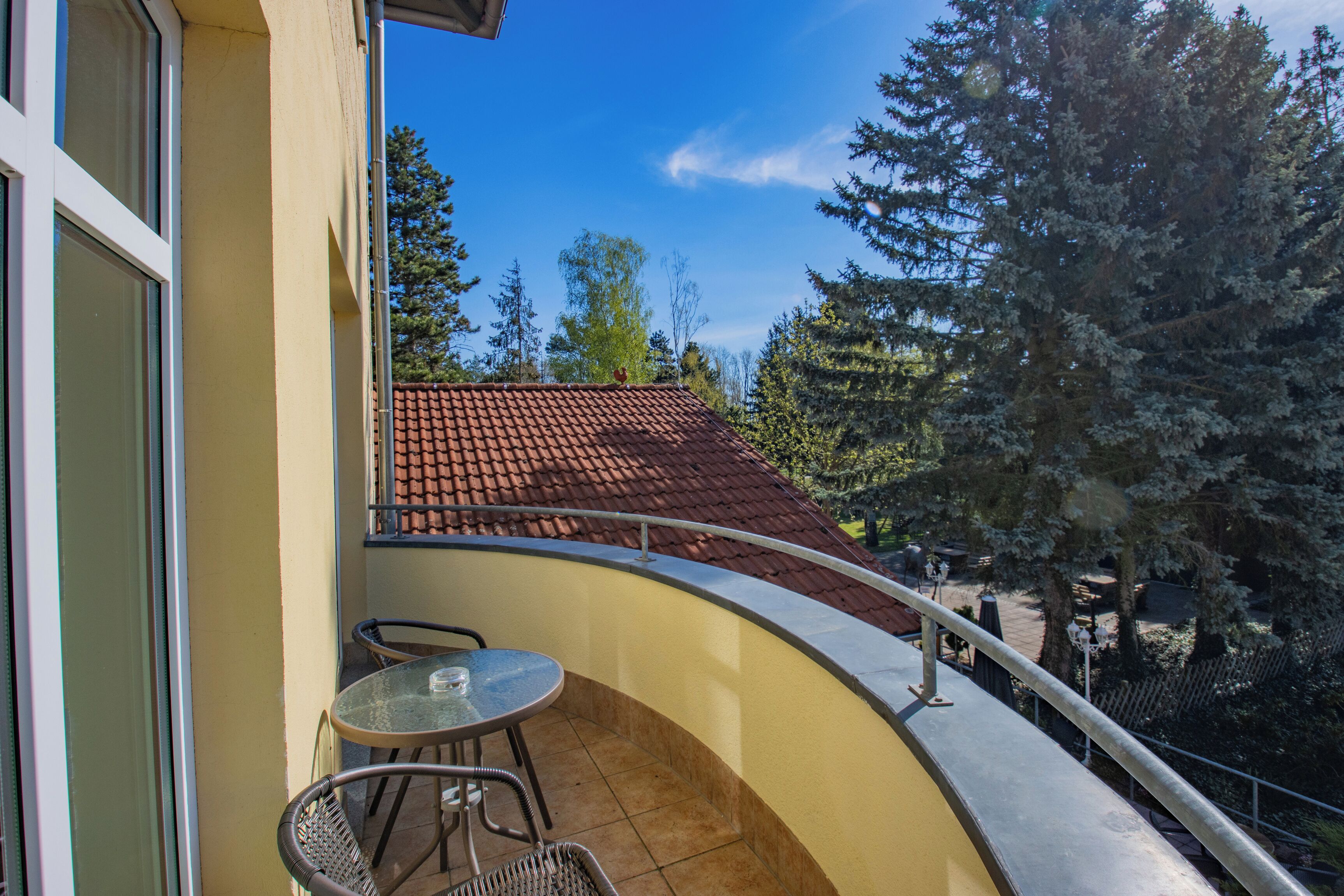 Ein Balkon mit geschwungener Geländer, einem kleinen Tisch und zwei Stühlen.