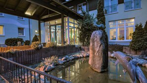 A building with a pond, a large rock, and a dolphin statue. - Ferien Hotel Spree-Neiße (Neuhausen/Spree)
