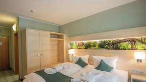 A hotel room with a bed, a wardrobe, a nightstand, and a view of a bridge and greenery. - Ferien Hotel Spree-Neiße (Neuhausen/Spree)