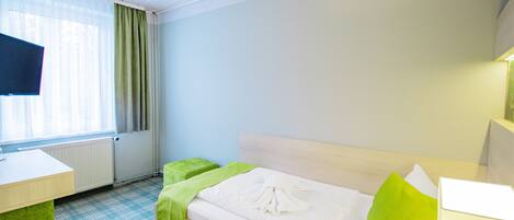 A hotel room with a bed, a desk, a chair, and a television.