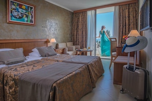 A hotel room with two beds, a sitting area, a balcony, and a view of the outdoors. - Hotel Mediteran Conference & Spa resort (Becici)