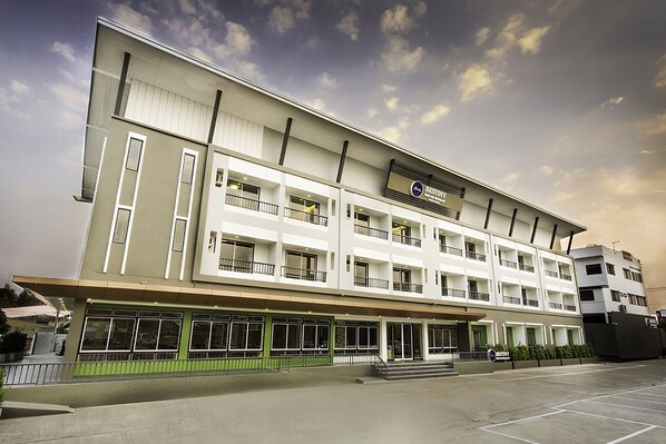 A multi-story hotel with a flat facade, large windows, and a green entrance area. - Bestiny Hotel and Restaurant PHETCHABUN (Nong Phai)