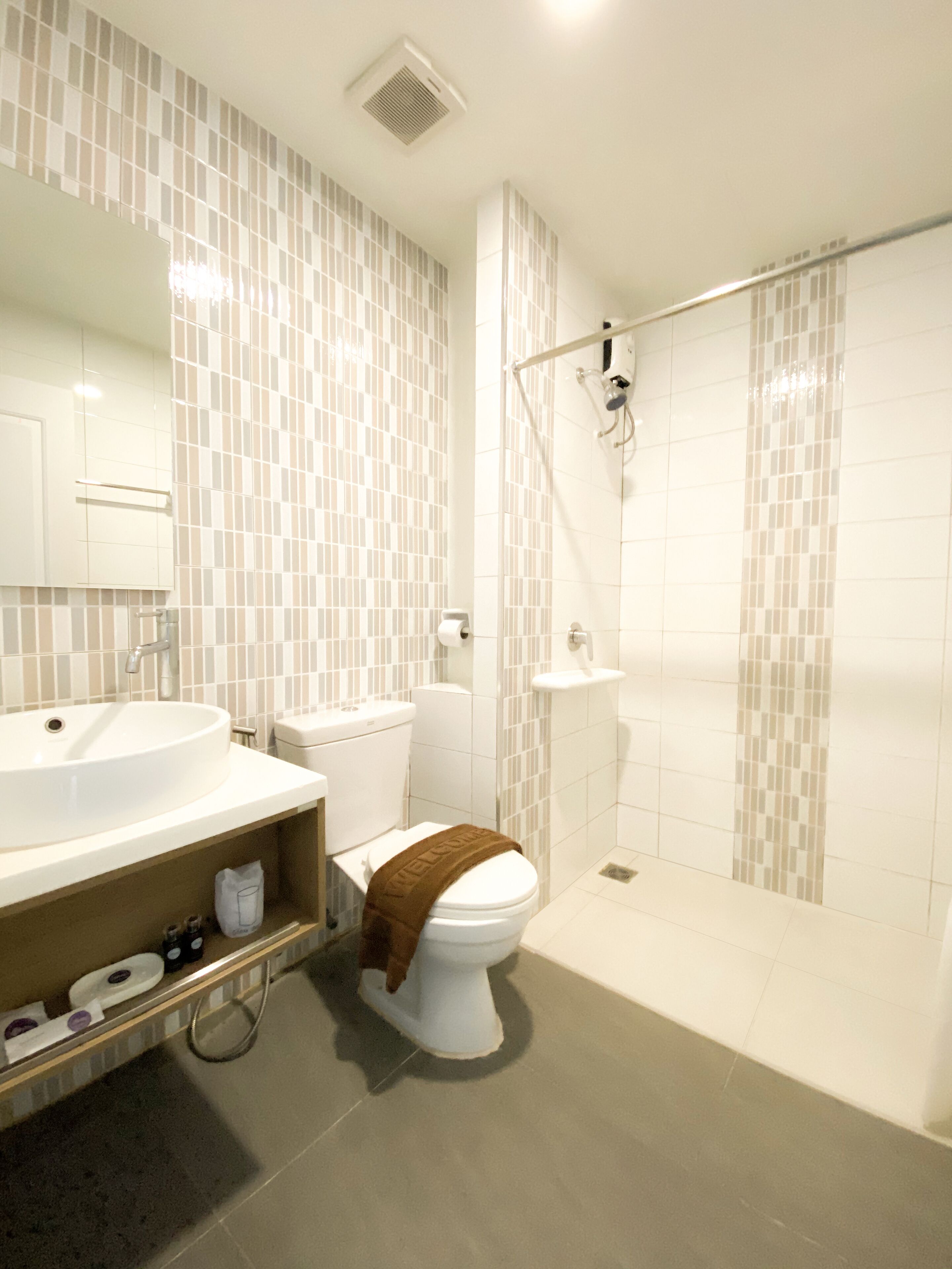 Un baño moderno con lavamanos, inodoro y zona de ducha blancos.