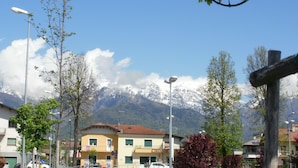A building with a yellow facade, a balcony, and a mountain backdrop. - B&B Villa Norma (Feltre)