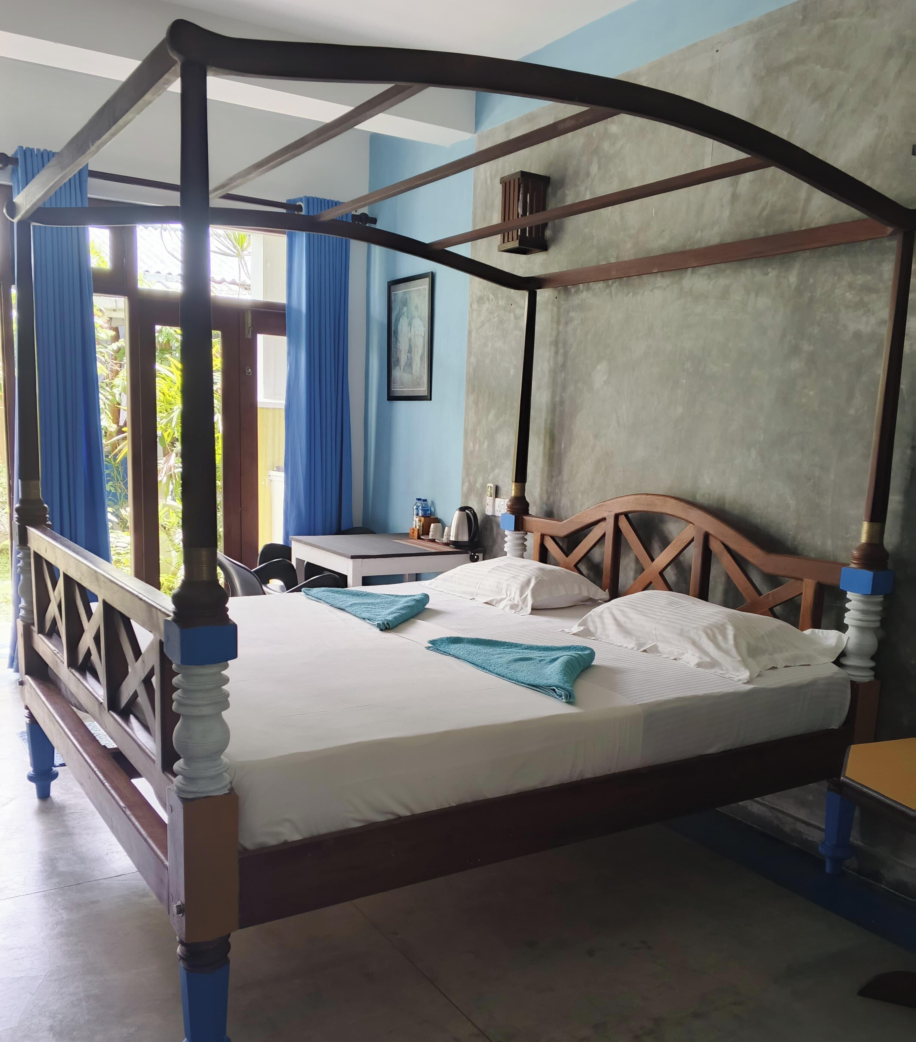 Uma cama de dossel com cabeceira de madeira, uma mesa de cabeceira com chaleira e um quadro pendurado na parede.