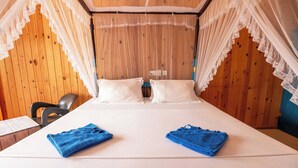 A bed with white linens, a canopy, and two blue towels. - Aaradhya Mirissa (Mirissa)
