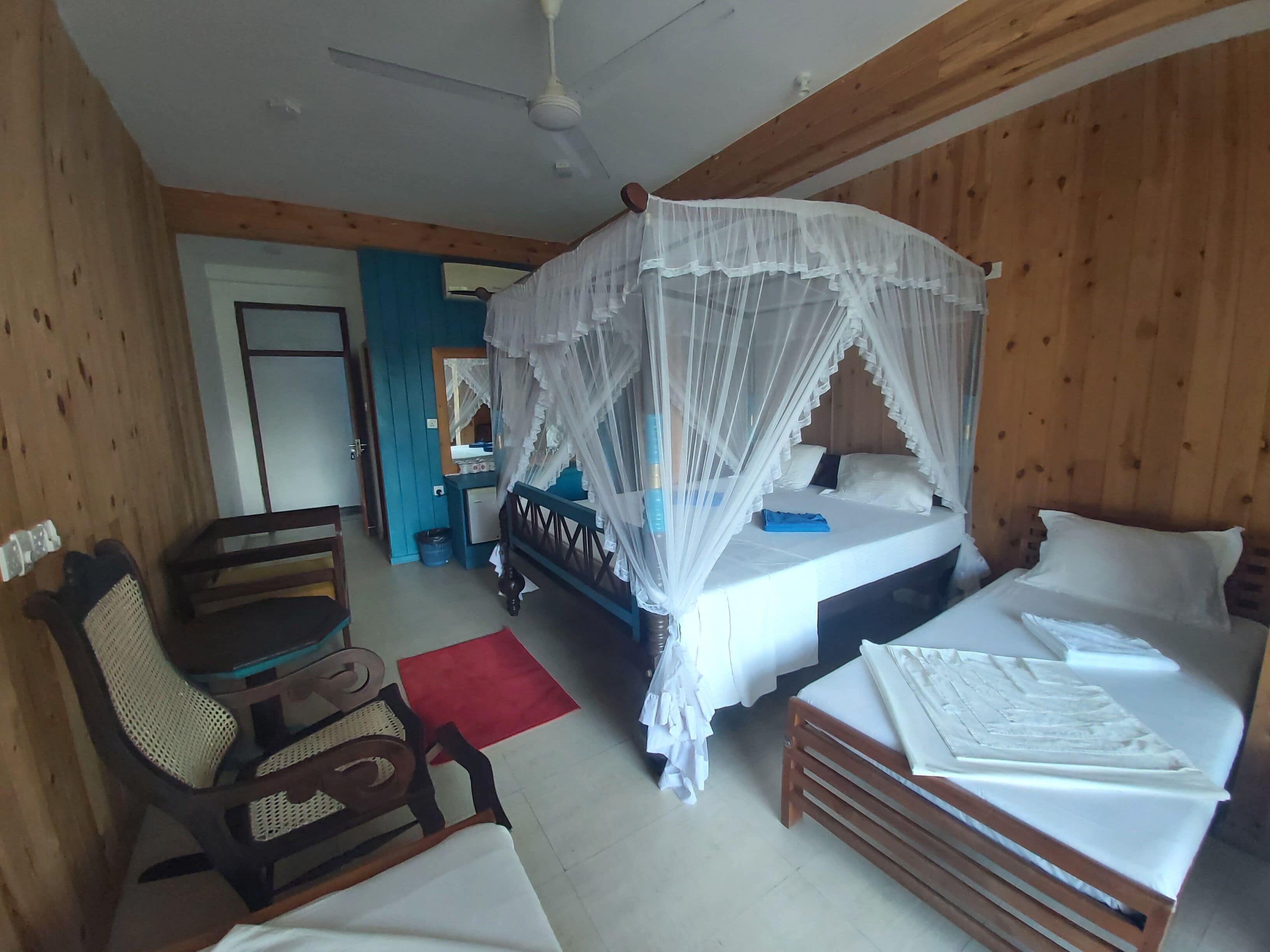 A bedroom with a canopy bed, a desk, a chair, and a wardrobe.