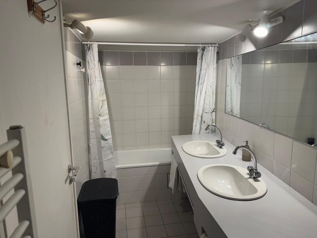 Une salle de bain avec deux lavabos, une douche et un miroir.