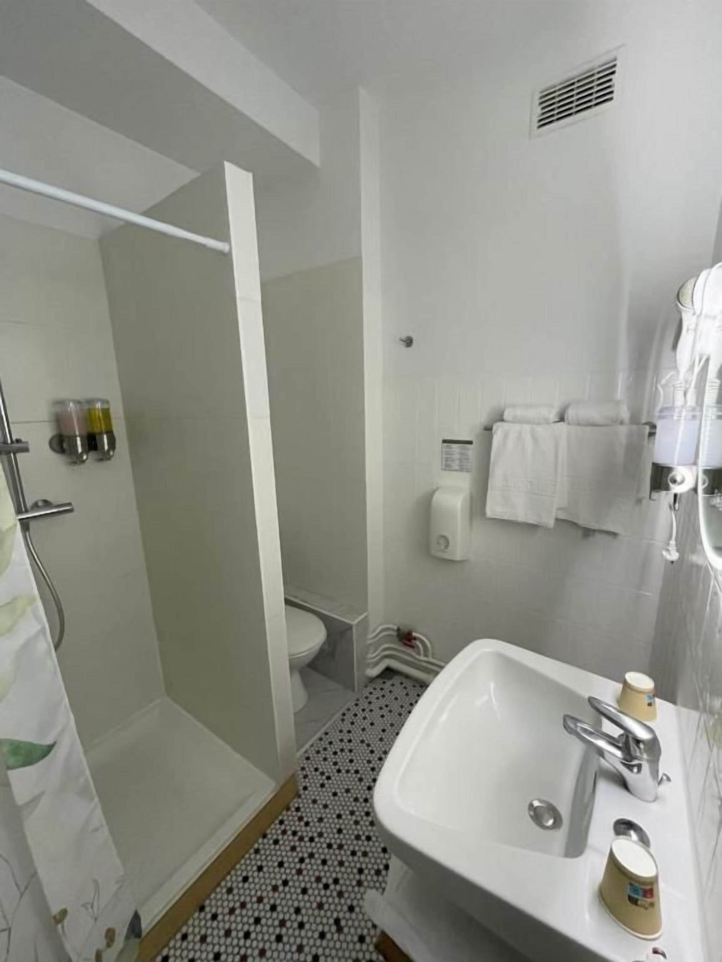 Een badkamer met douche, toilet, wastafel en handdoekrek.