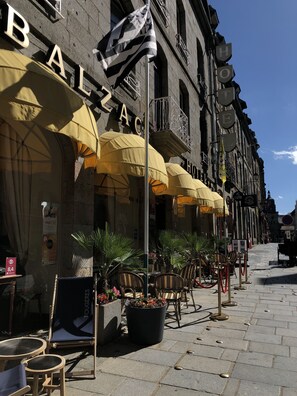 A row of outdoor seating with yellow umbrellas, a flag, and a sign for a hotel named "BALZA". - Balzac Hôtel (Fougeres)