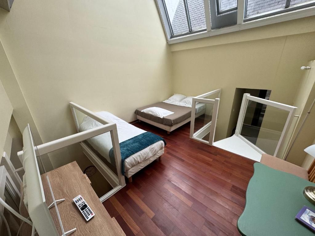 Una habitación pequeña con dos camas, una mesita y una ventana.