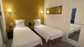 A hotel room with two single beds, a bedside table with a lamp, a mirror, and a door leading to another room. - Balzac Hôtel (Fougeres)