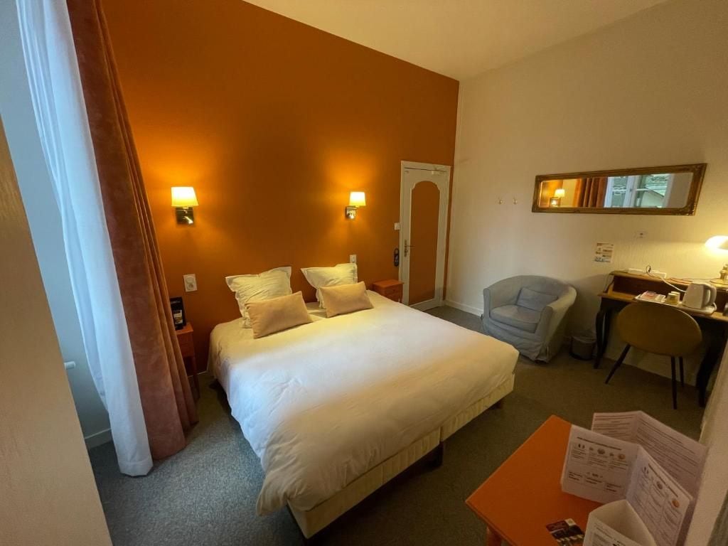 Ein Hotelzimmer mit einem großen Bett, zwei Nachttischlampen, einem Schreibtisch mit Stuhl und einem Spiegel an der Wand.
