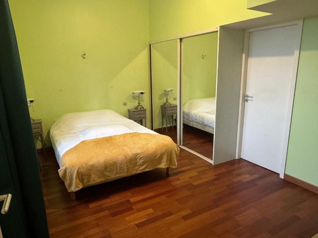 A bedroom with a bed, a nightstand, a mirror, and a wardrobe.