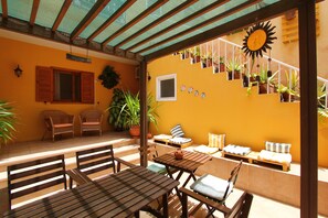Eine Terrasse im Freien mit Holzmöbeln, Topfpflanzen und einer Sonnenuhr.