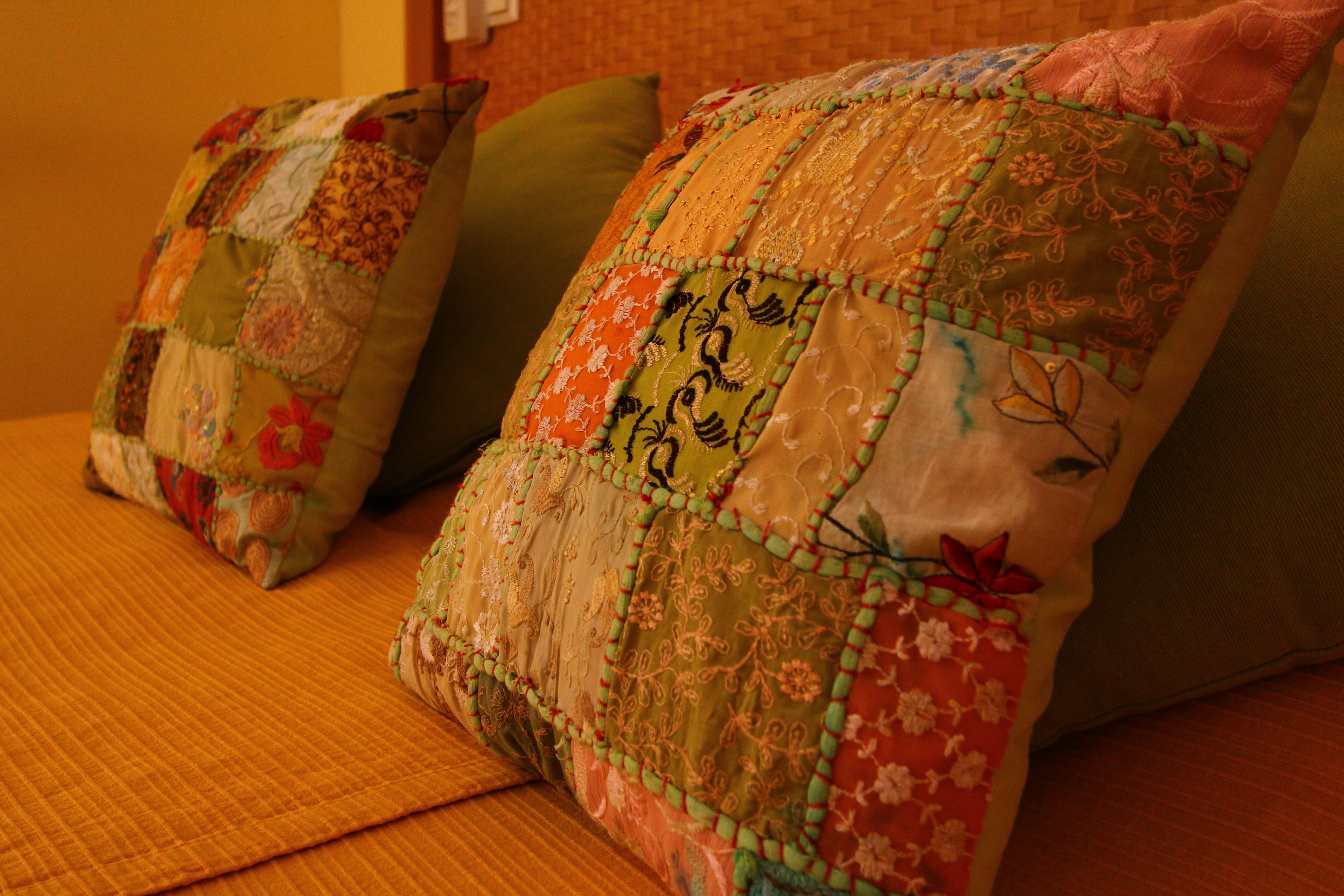 Two pillows with patchwork designs on a bed.