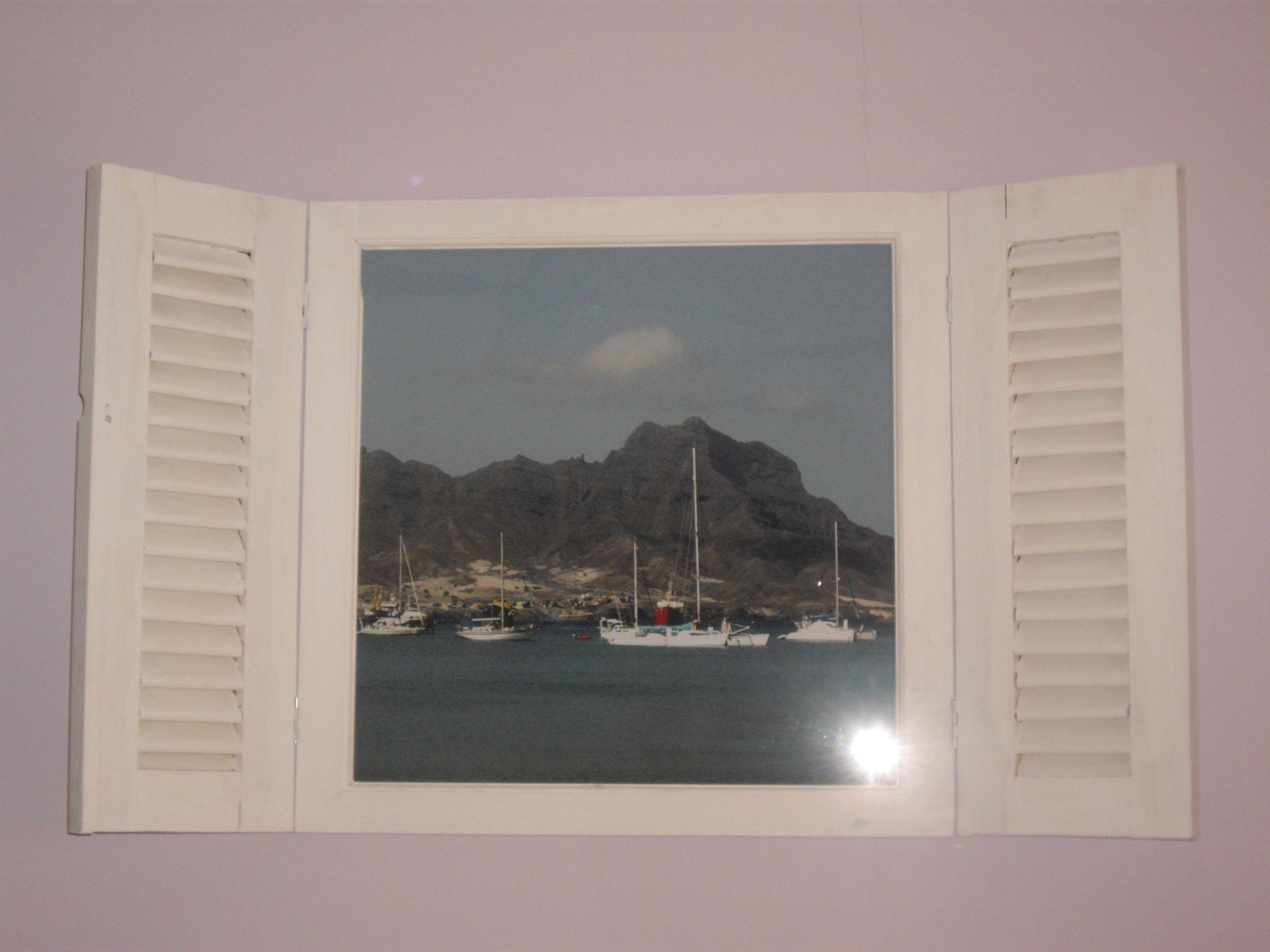 A framed photograph of a coastal scene with boats and a mountain.