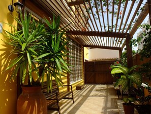 A covered patio area with potted plants, wooden benches, and a pergola structure. - Kira's Boutique Hotel (São Vicente)