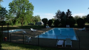 A swimming pool with lounge chairs and a fenced area.