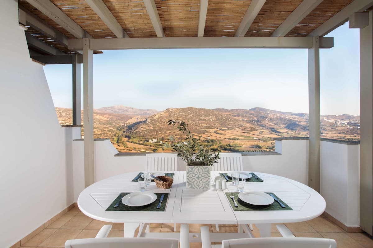 A dining area with a table set for two, overlooking a mountainous landscape.