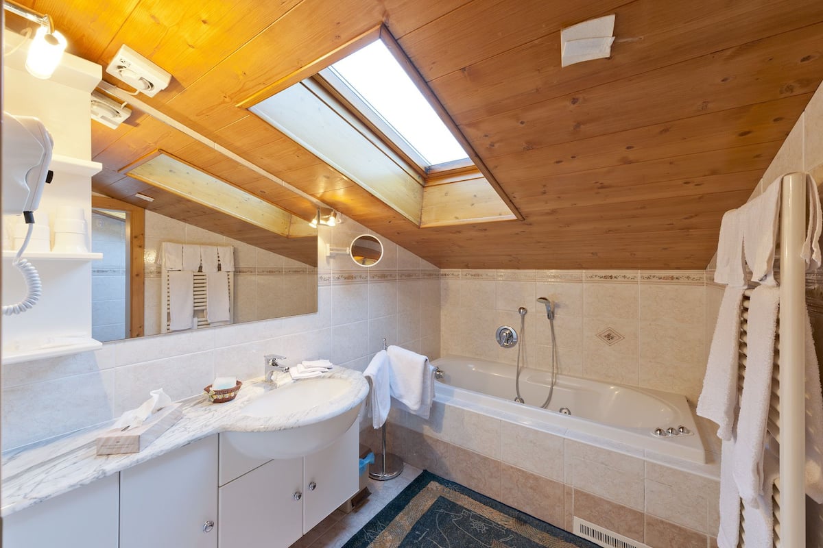 Ein modernes Badezimmer mit Dachfenster, einer Badewanne und einem Waschtisch mit Spiegel.