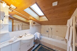 Un baño moderno con tragaluz, bañera y tocador con espejo.