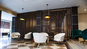 A lobby with checkered flooring, white and teal chairs, and a modern wooden partition. - Chagala Residence Atyrau (Atyrau)