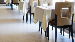 A restaurant with tables and chairs, large windows, and hanging pendant lights. - Chagala Residence Atyrau (Atyrau)