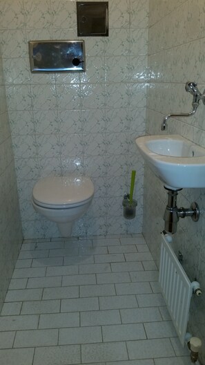 A bathroom with a toilet, a sink, and a shower. - Goldfisch Apartment Central Park (Vienna)