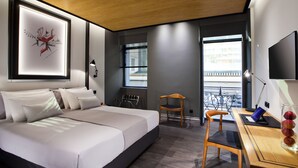 Una habitación de hotel moderna con una cama grande, un escritorio con una computadora portátil, una silla y un televisor.