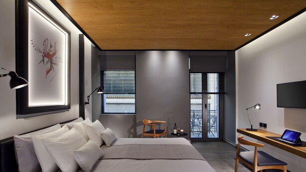 Un dormitorio moderno con una cama grande, un escritorio con una computadora portátil y un televisor.