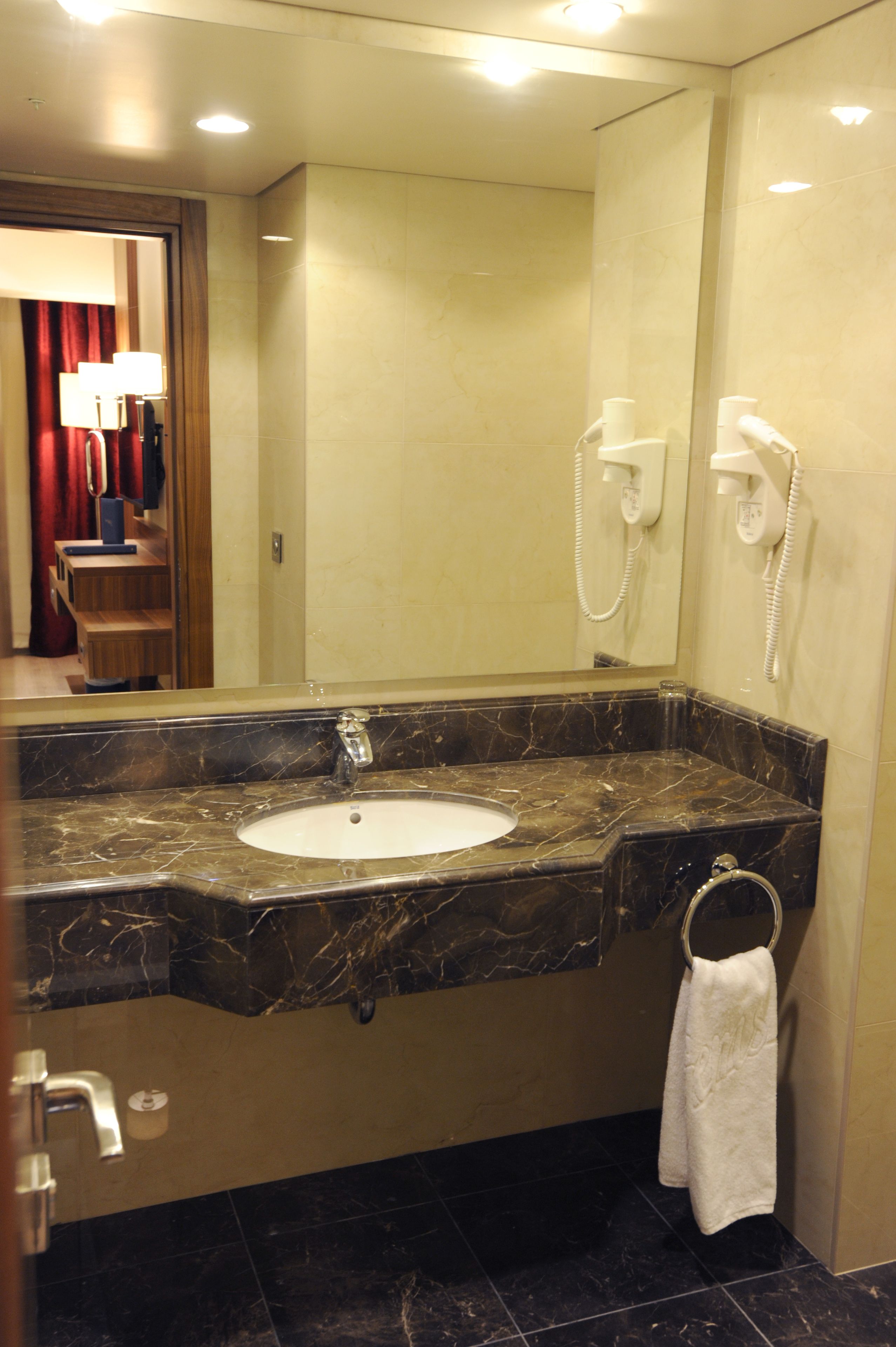 Une salle de bain avec un lavabo en marbre, un porte-serviettes et un miroir.