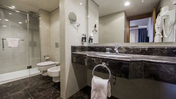 A modern bathroom with a glass-enclosed shower, a marble sink, and a large mirror.