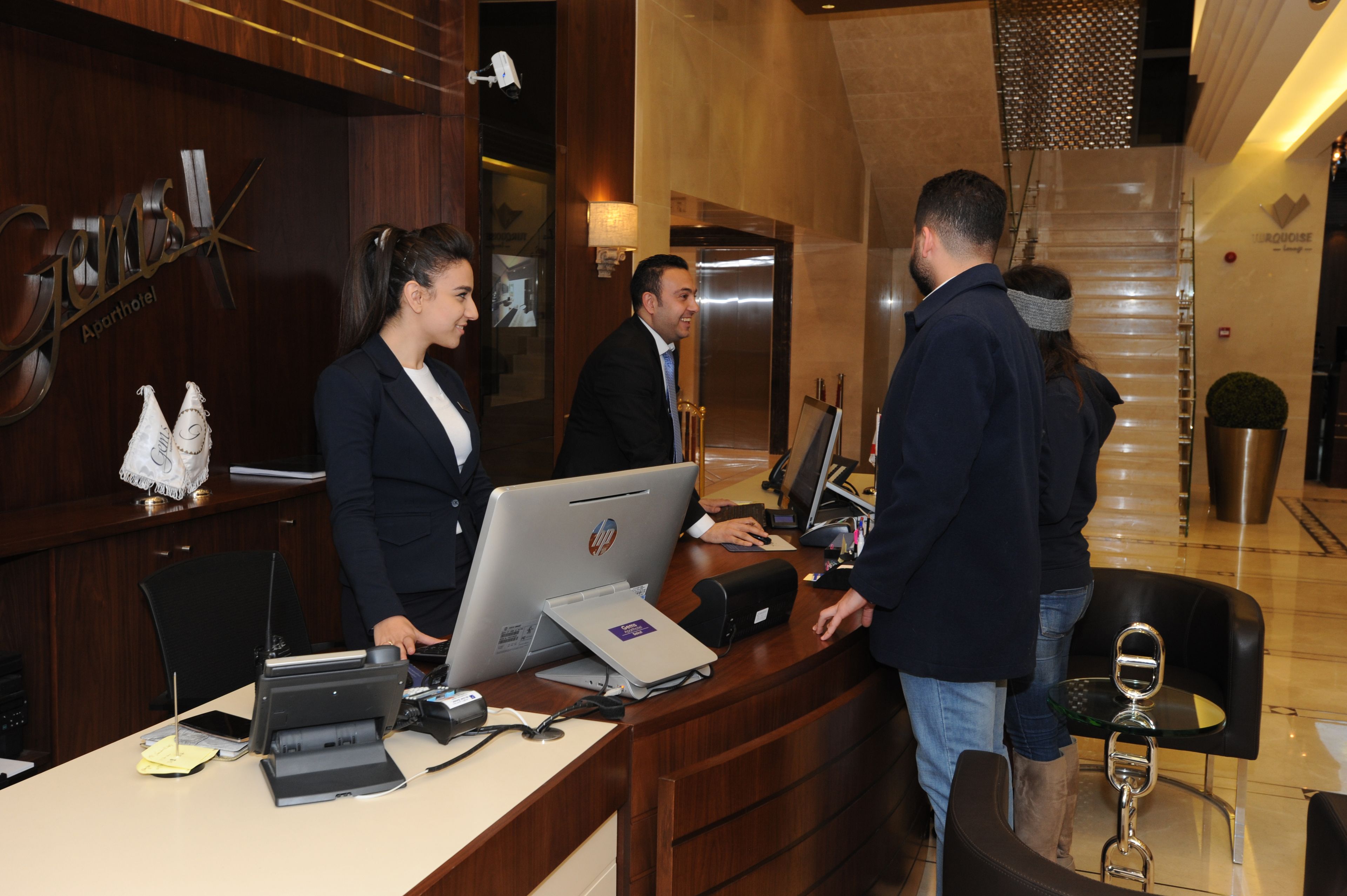 Un comptoir d’accueil dans le hall d’un hôtel, avec un bureau en bois, un ordinateur et un téléphone.