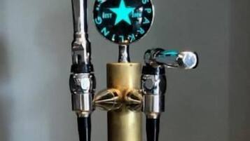 A tap with a star-shaped spigot and a pressure gauge, surrounded by empty glasses on a tray.