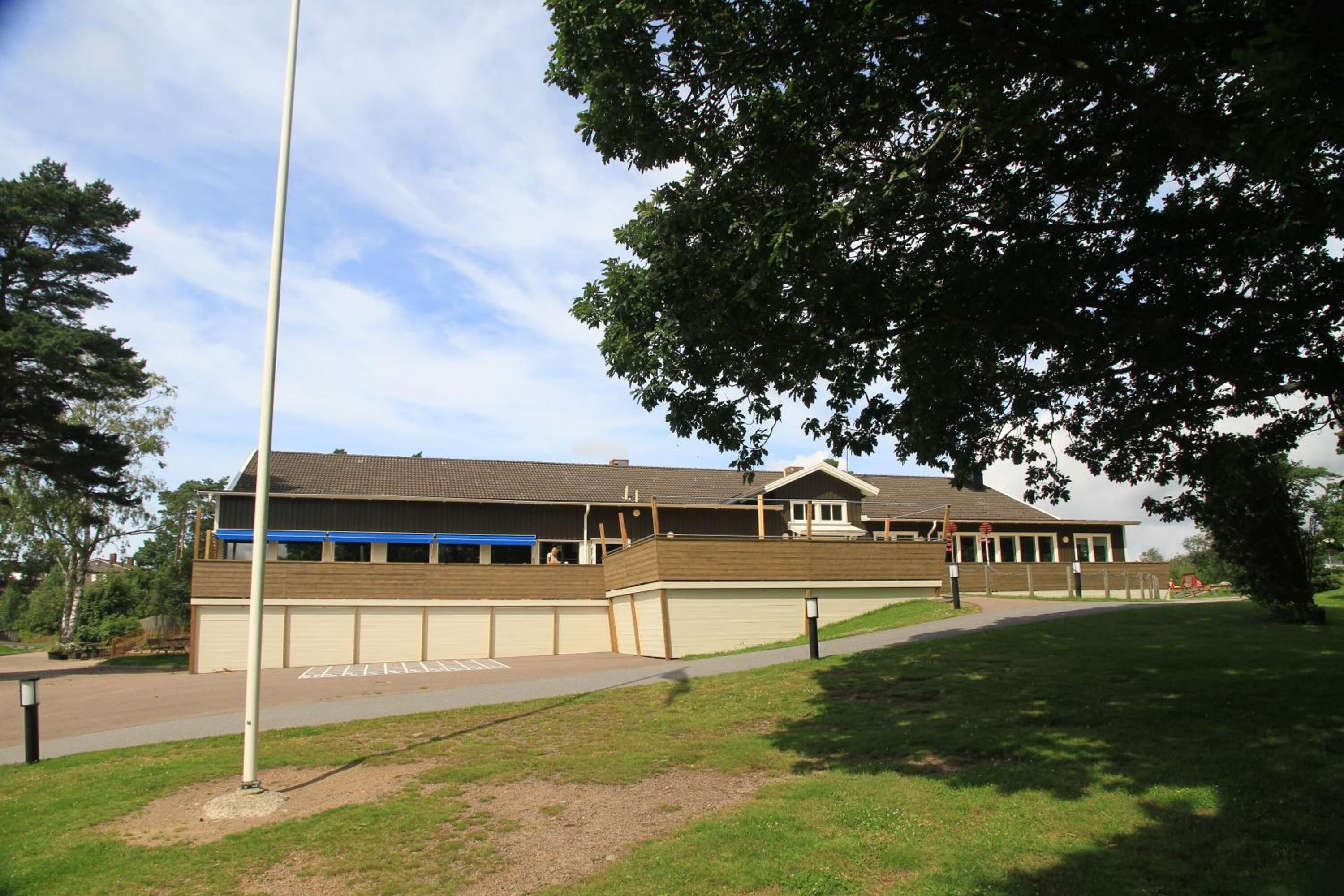 A building with a flat roof, a covered walkway, and a parking area.