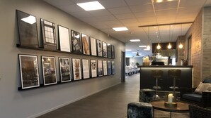 A hallway with framed artwork on the walls, a seating area with a round table, and a reception desk in the background. - Gottskär Hotell & Konferens  (Gottskar)