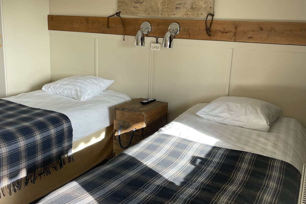 A room with two beds, a wooden headboard, a map on the wall, and a small wooden chest.