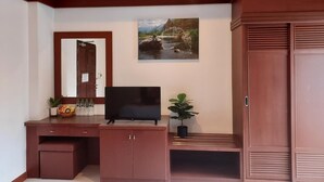 A room with a wooden desk, a television, a mirror, a wardrobe, and a painting of a river scene. - Naithon Beach Mansion (Sa Khu)