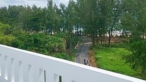 A view of a road surrounded by trees and greenery, with a white fence in the foreground. - Naithon Beach Mansion (Sa Khu)