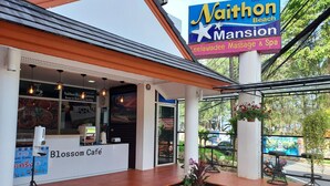 A café named 'Blossom Café' with a sign for 'Naithon Beach Mansion' and 'Leelawadee Massage & Spa' visible. - Naithon Beach Mansion (Sa Khu)