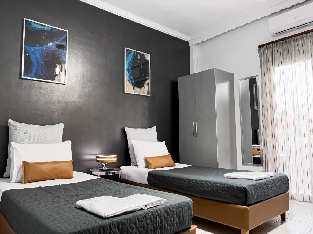A hotel room with two beds, a wardrobe, and artwork on the walls.