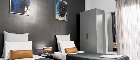A hotel room with two beds, a wardrobe, and artwork on the walls.