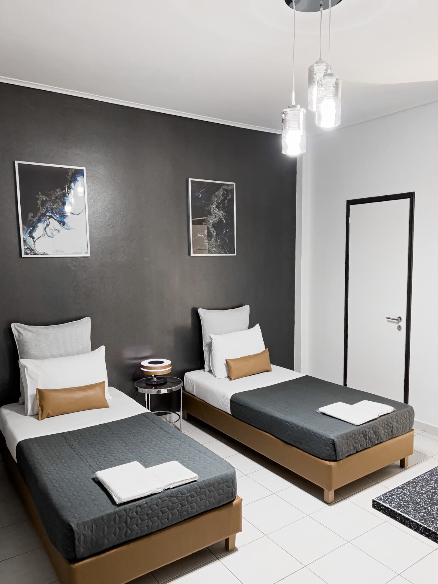 Una habitación de hotel moderna con dos camas, una mesita de noche y una puerta.