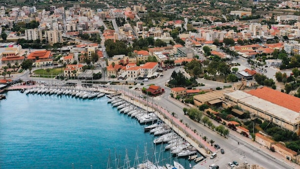 A coastal cityscape with a marina filled with boats, surrounded by residential buildings and greenery.